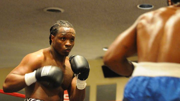 Two men are boxing in a ring and one is looking at the other