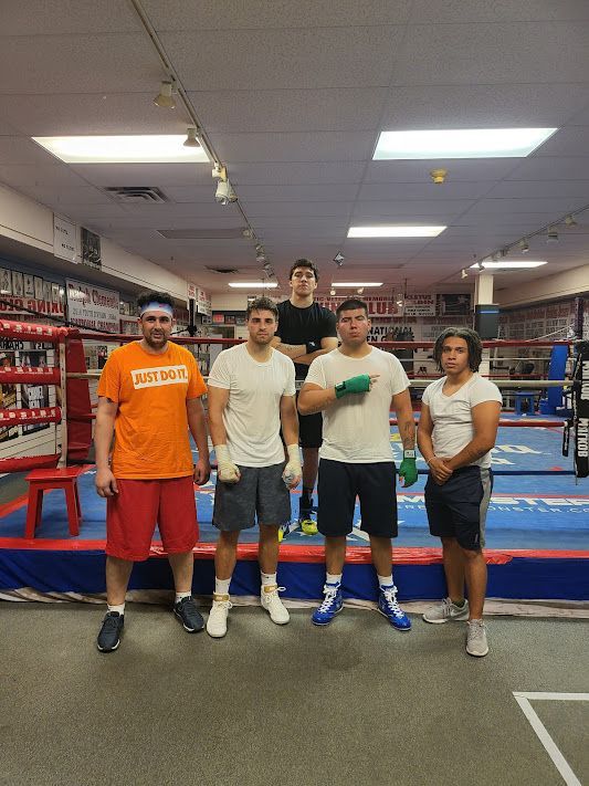 A group of people are posing for a picture in a boxing ring.
