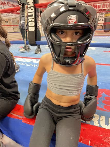A little girl wearing boxing gloves and a helmet