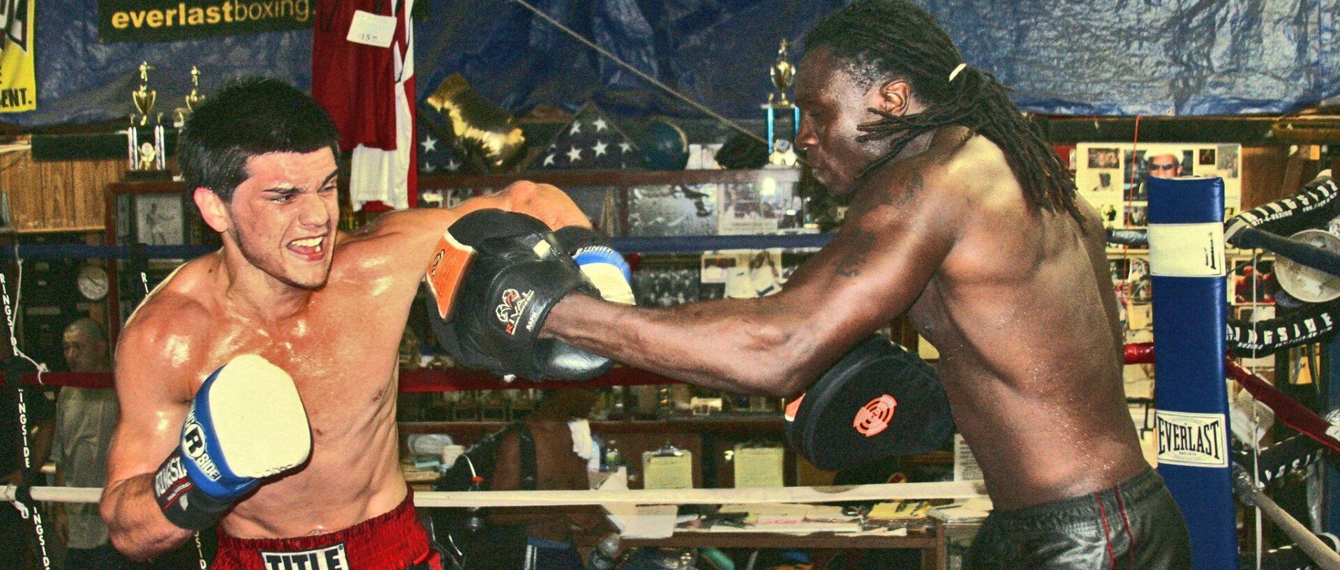 Two men are boxing in a ring and one of them is wearing everlast gloves