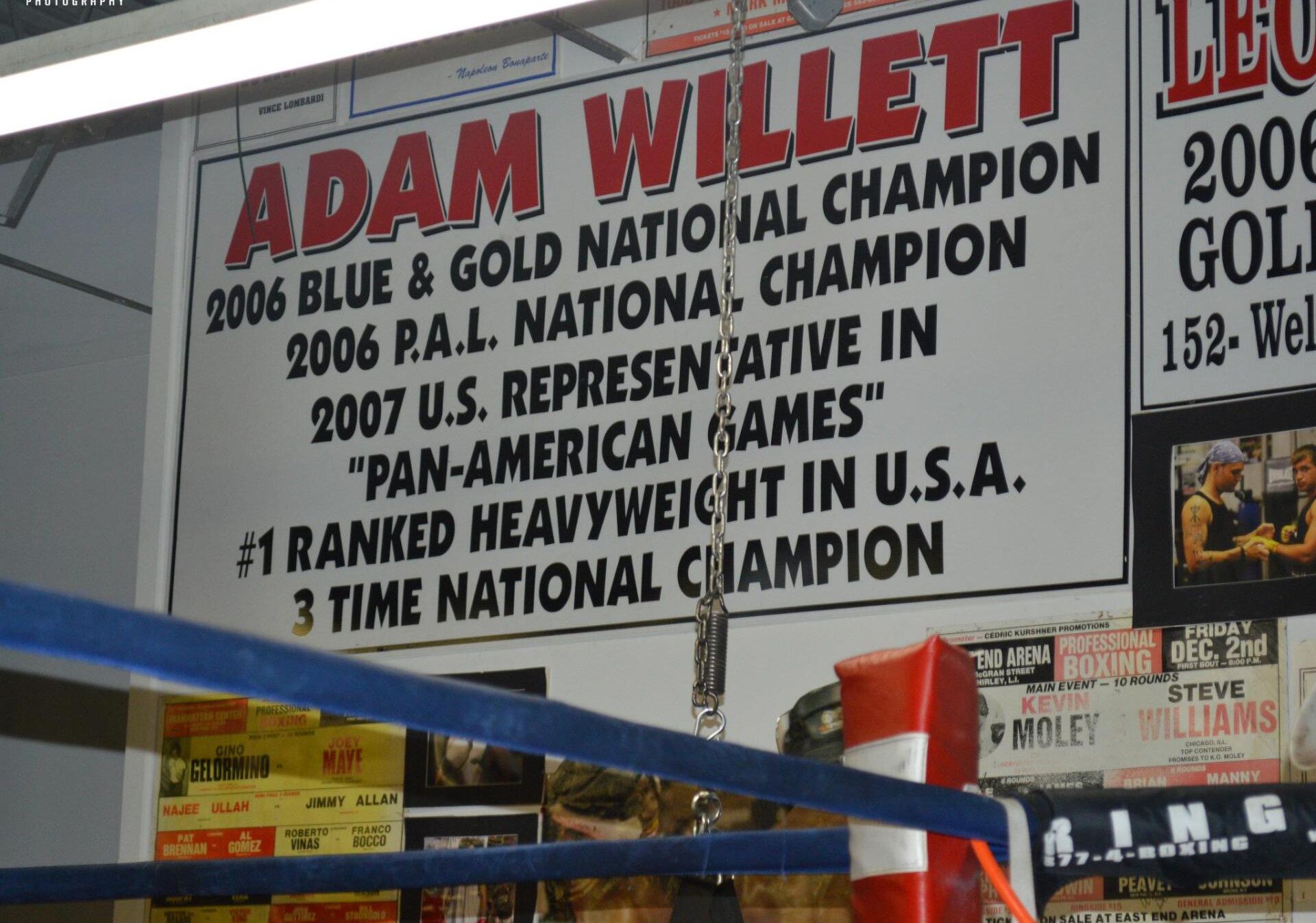 A sign for adam willett hangs above a boxing ring