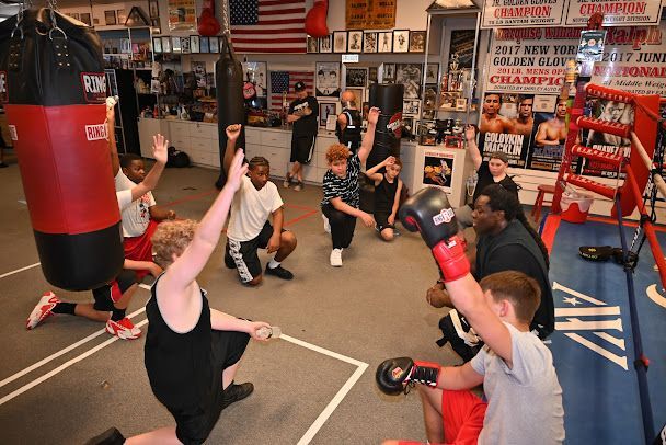A group of young boys are practicing boxing in a gym