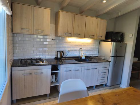 Cocina moderna con gabinetes de madera clara, salpicadero de azulejos blancos tipo metro