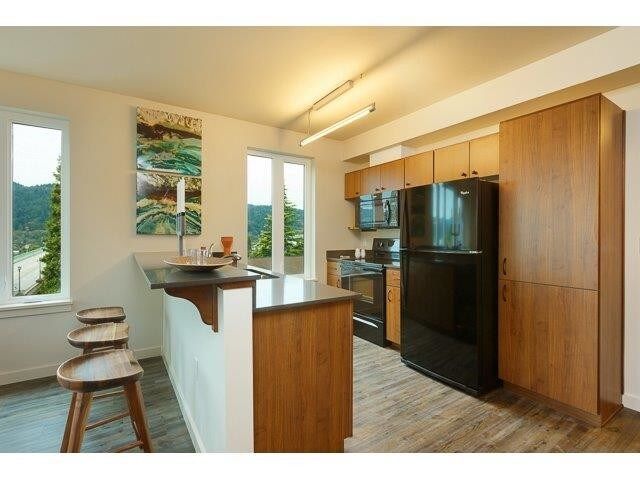A kitchen with a black refrigerator and wooden cabinets