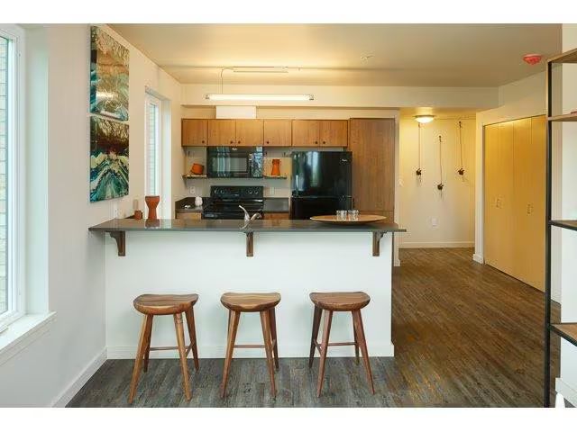A kitchen with a bar and three stools