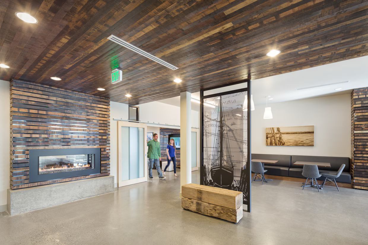 A couple of people are standing in a lobby with a fireplace.