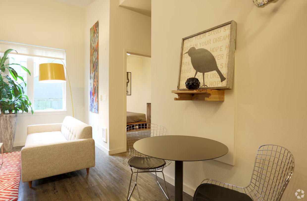 A living room with a couch , table , chairs and a picture of a bird on the wall.