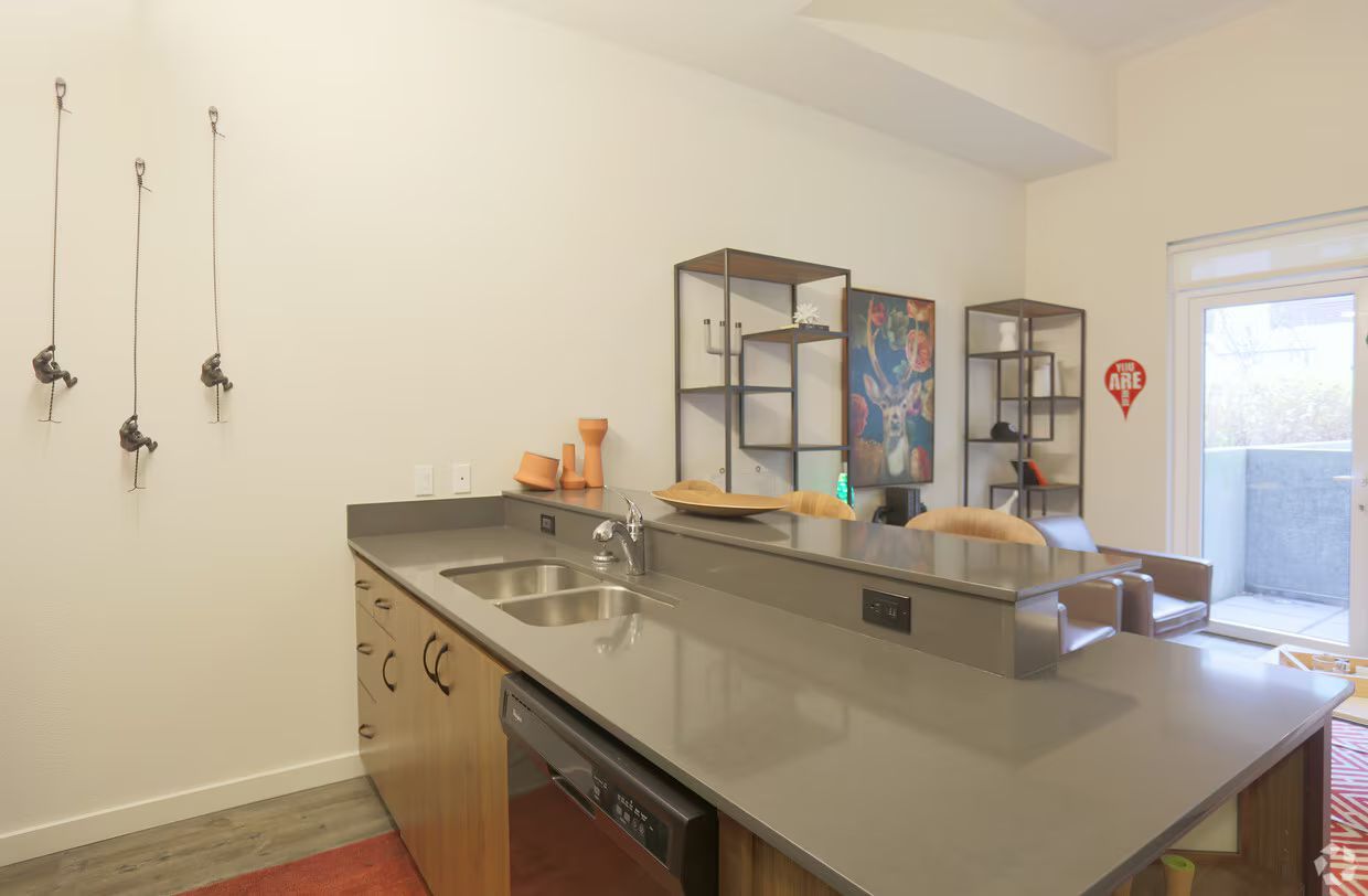 A kitchen with a sink , dishwasher , and sliding glass door.