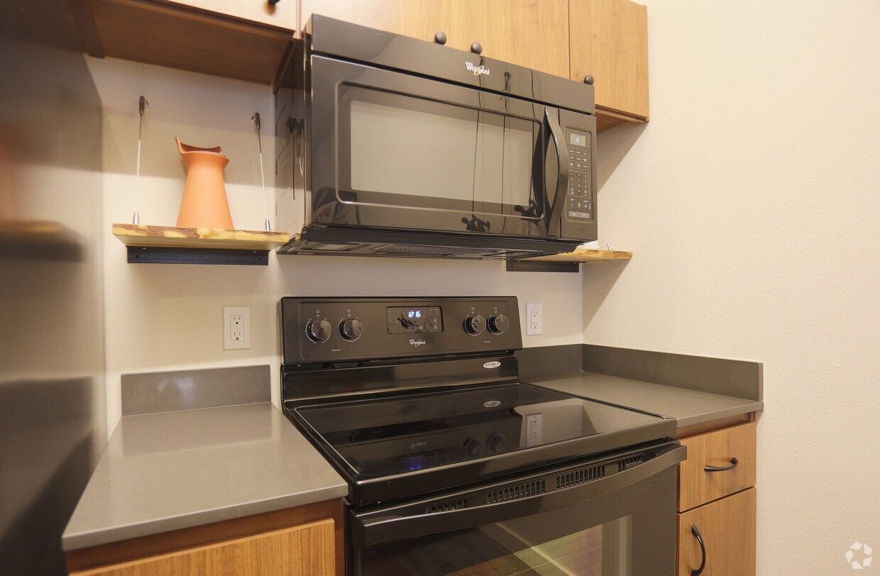 A kitchen with a stove , microwave , and refrigerator.