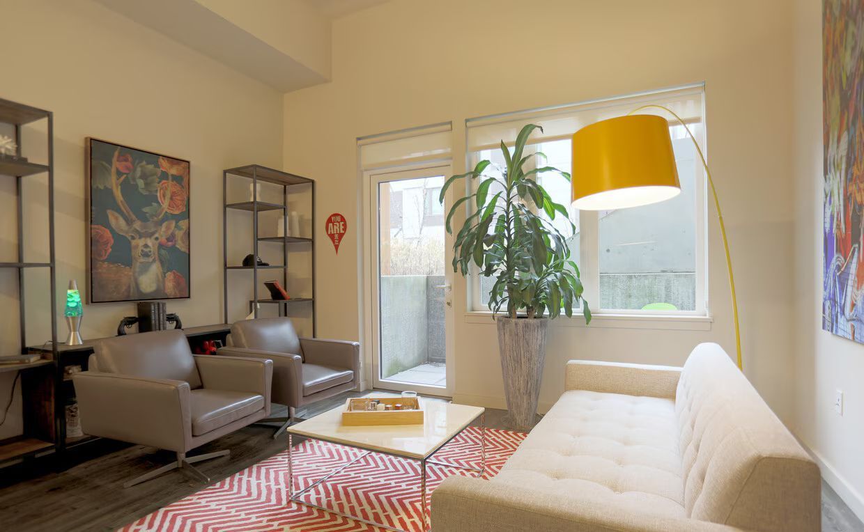 A living room with a couch , two chairs , a coffee table and a plant.