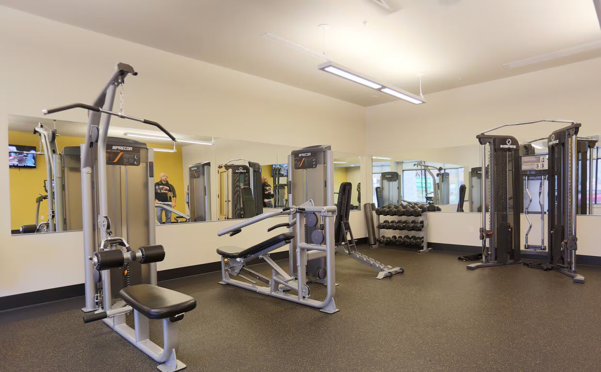 A large gym filled with lots of exercise equipment.