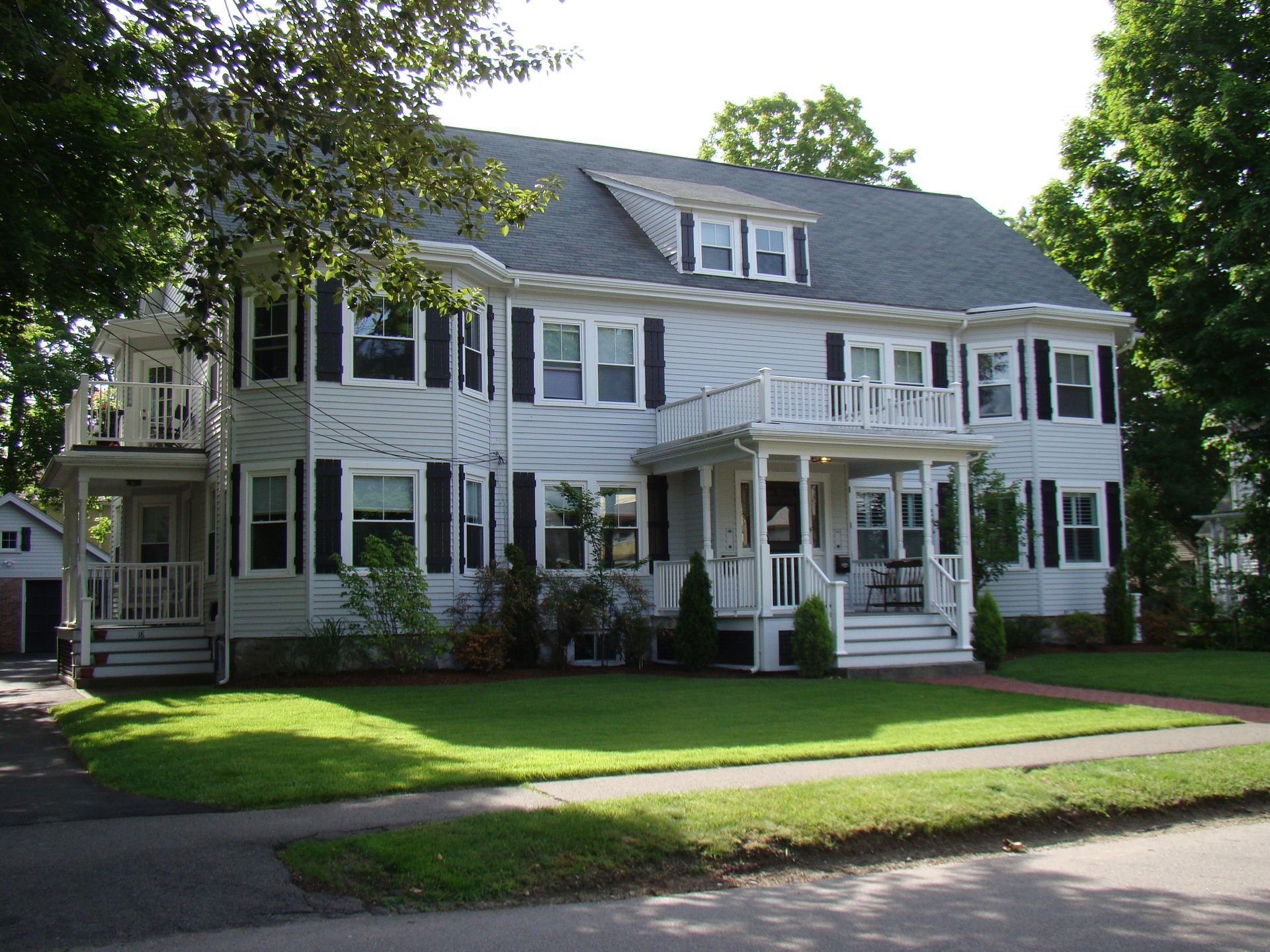A large white house with black shutters and a porch