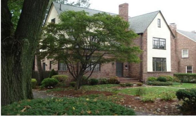 A large brick house with a tree in front of it