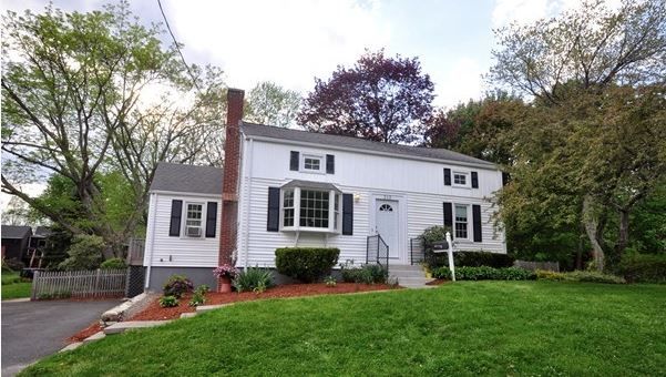 A white house with black shutters and a brick chimney