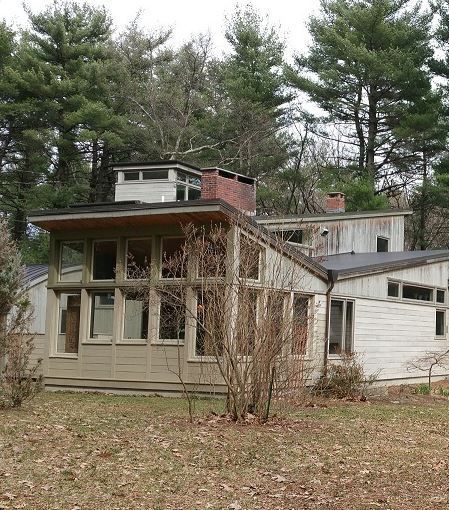 A house in the middle of a forest with trees in the background