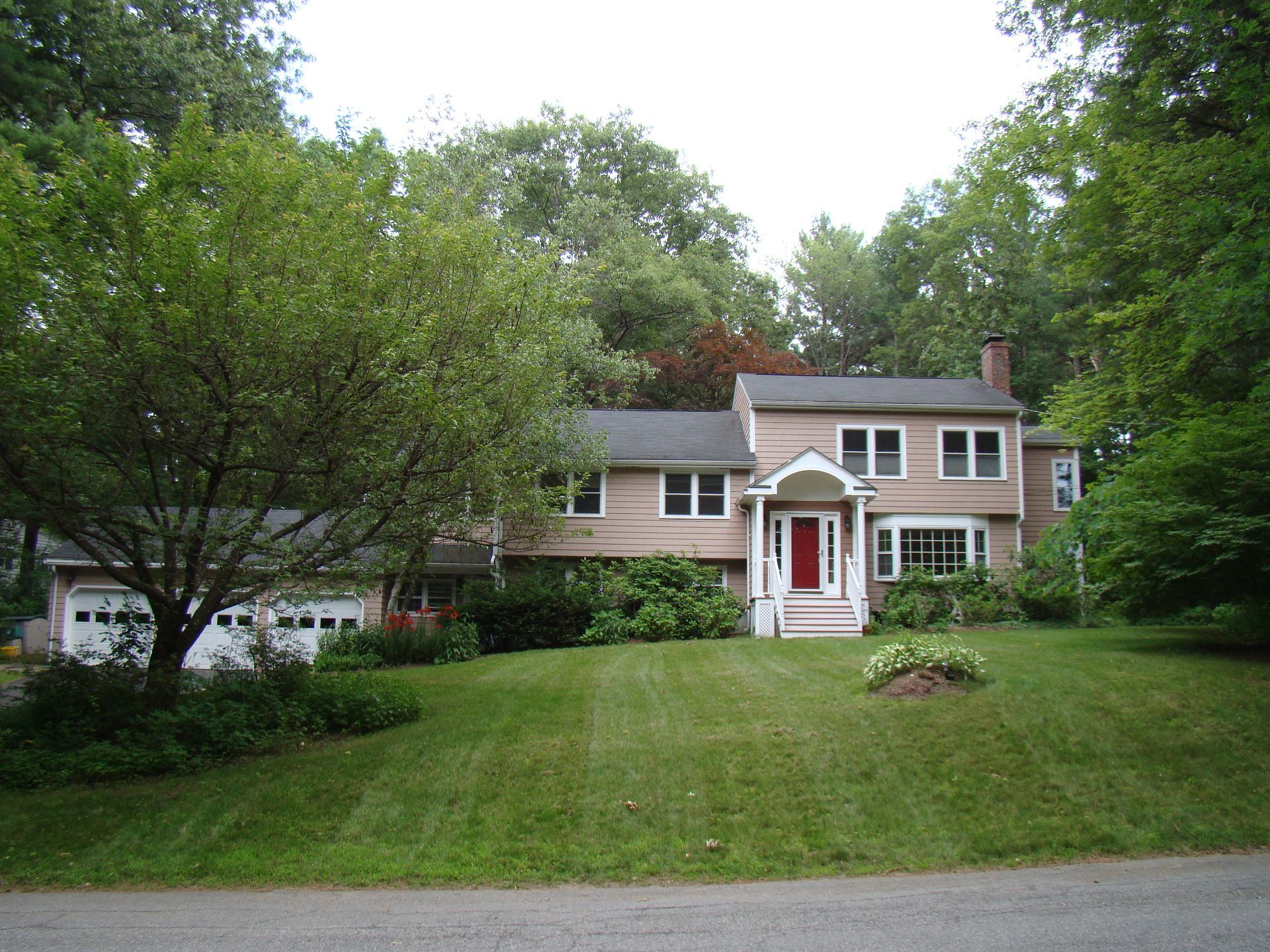 A house with a red door is surrounded by trees