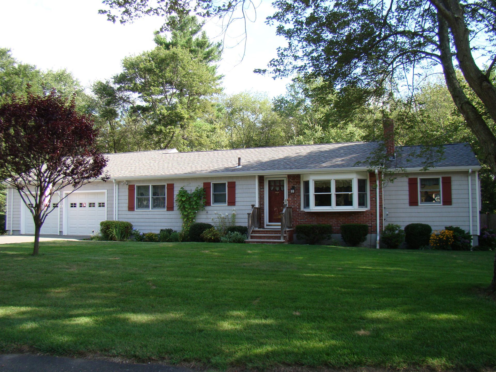 A white house with red shutters and a lush green lawn