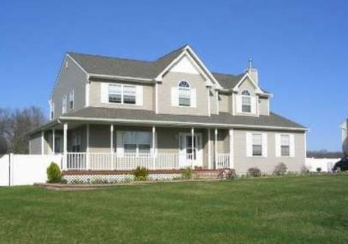 A large house with a porch and a white fence