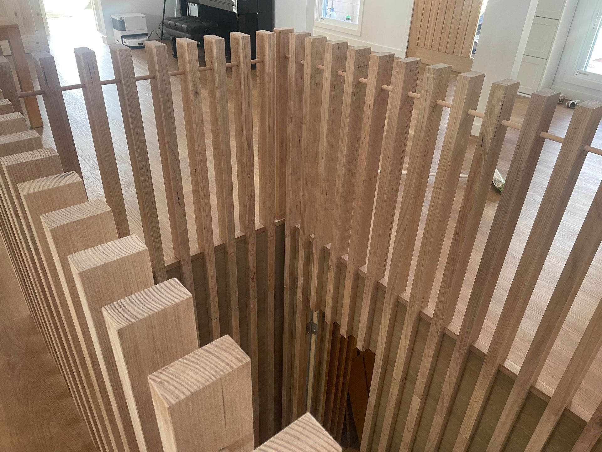 Wooden slatted stair railing, interior view. Natural wood tones, angled design, open stairwell.