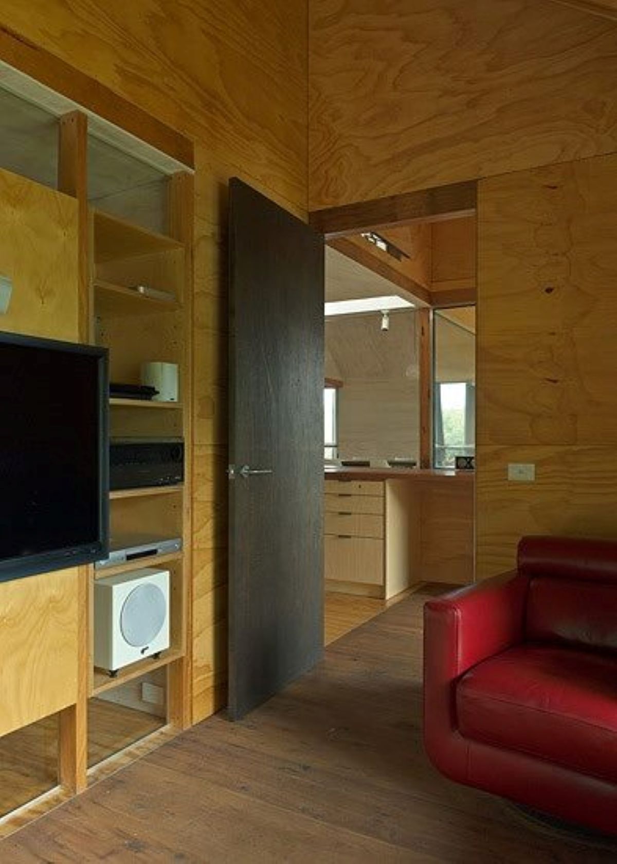 Interior View with Plywood Walls, Red Leather Chair, Dark Door — On The Rise Builders in North Arm, QLD