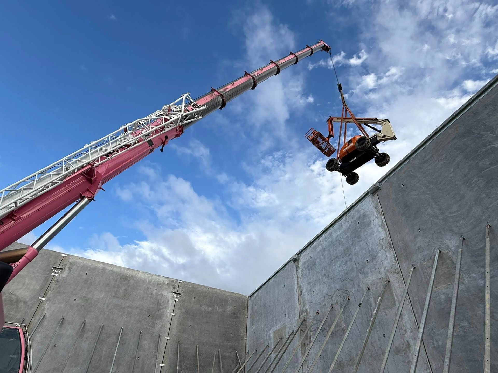 Pink Crane Lifting Over a Tall Concrete