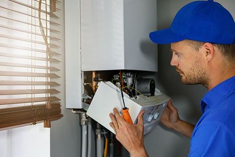 Man Fixing Heater — Bethesda, MD — Leahy Plumbing & Heating Inc.