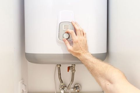Hands Setting The Temperature — Bethesda, MD — Leahy Plumbing & Heating Inc.