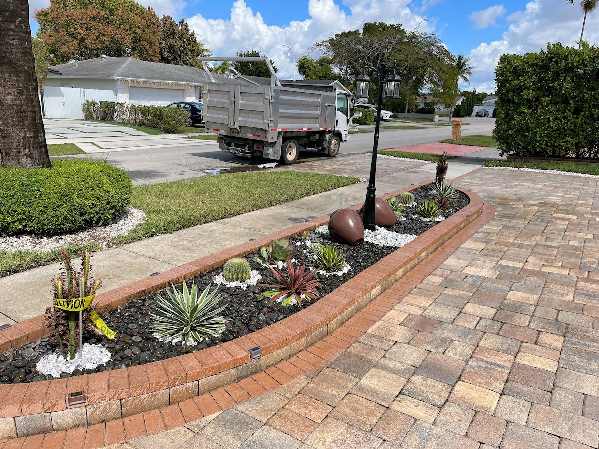 A dump truck is parked in a driveway next to a garden.