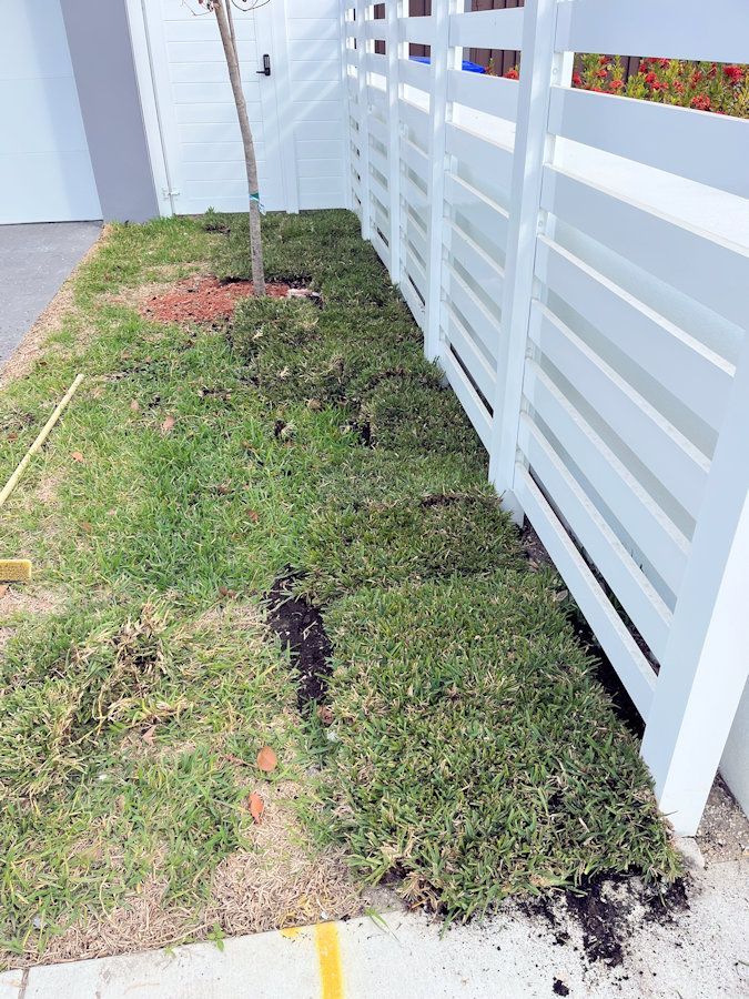 A white fence is surrounded by grass and dirt.