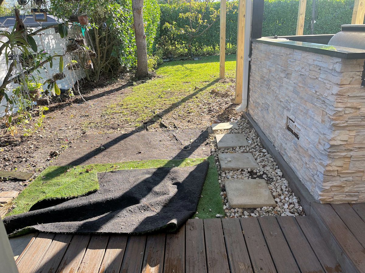 Dirt and some grass along a wall.