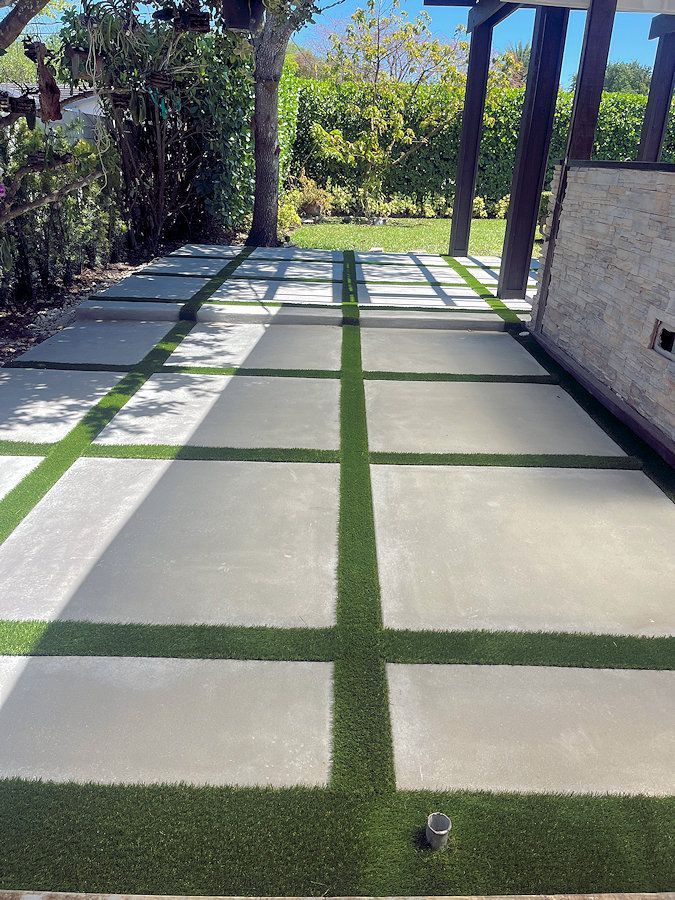 A patio with a concrete walkway and artificial grass.