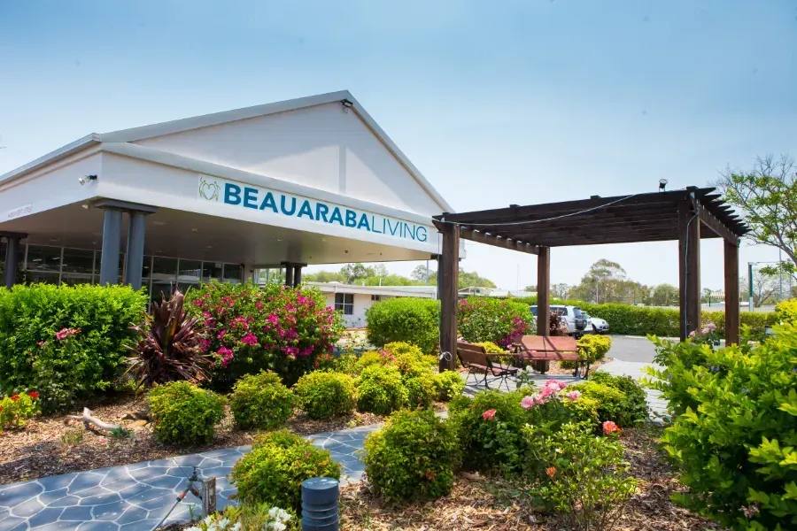 The front of the Beauaraba Living building surrounded by flowers and bushes.