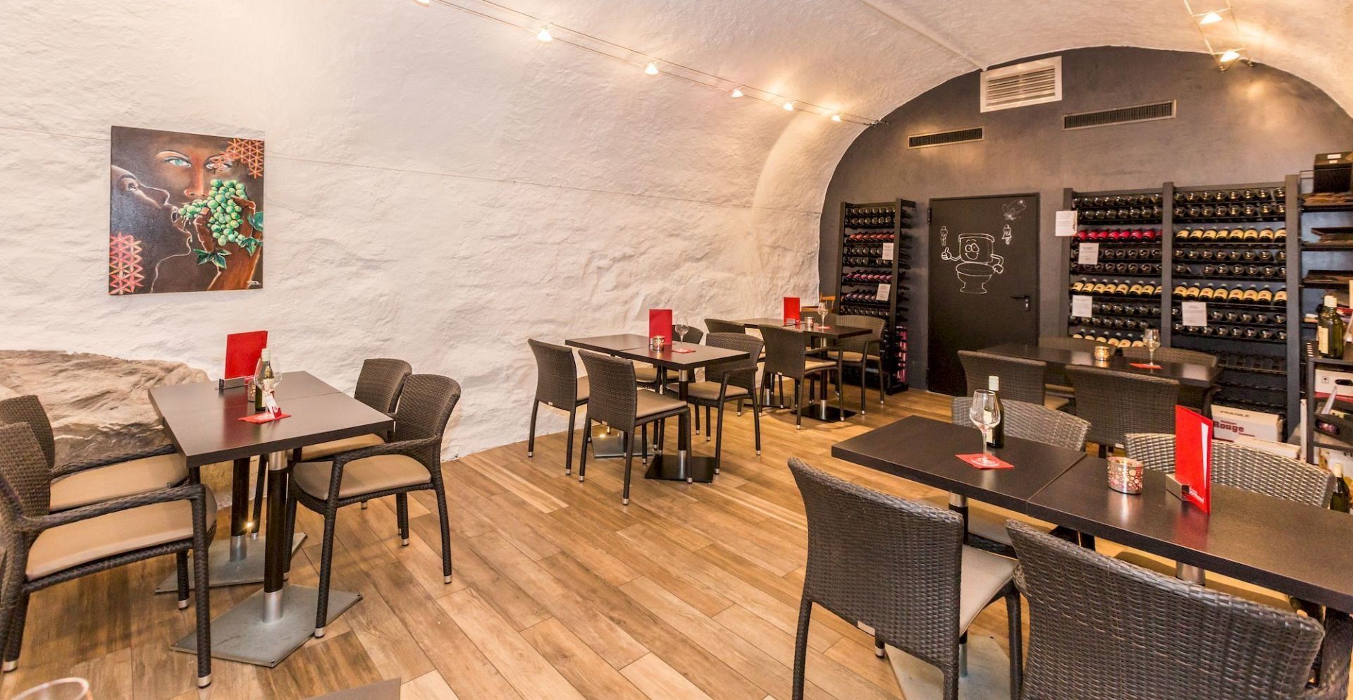 Un restaurant avec des tables et des chaises et un tableau sur le mur.