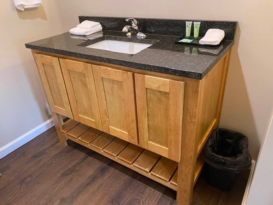 A bathroom vanity with a sink and a trash can.