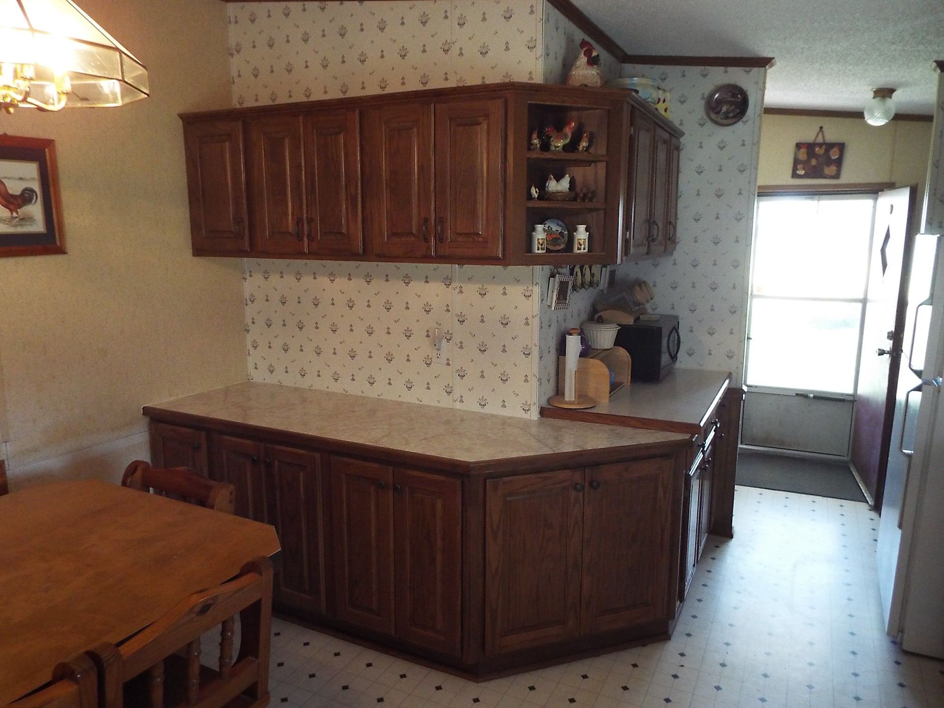 A kitchen with a table and chairs and a picture of a rooster on the wall
