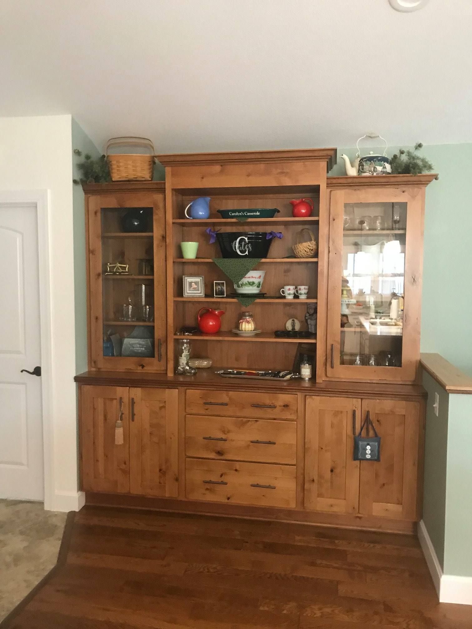 A wooden cabinet with glass doors and drawers in a living room.