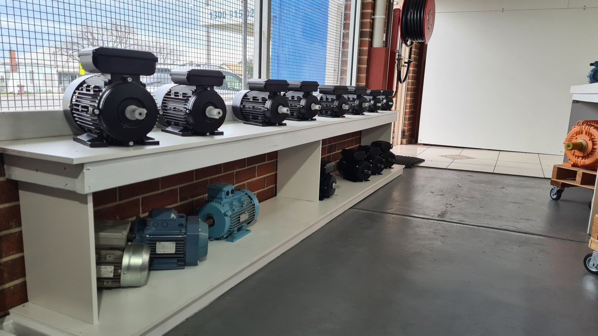 A row of blue and black electric motors sitting on top of a shelf.