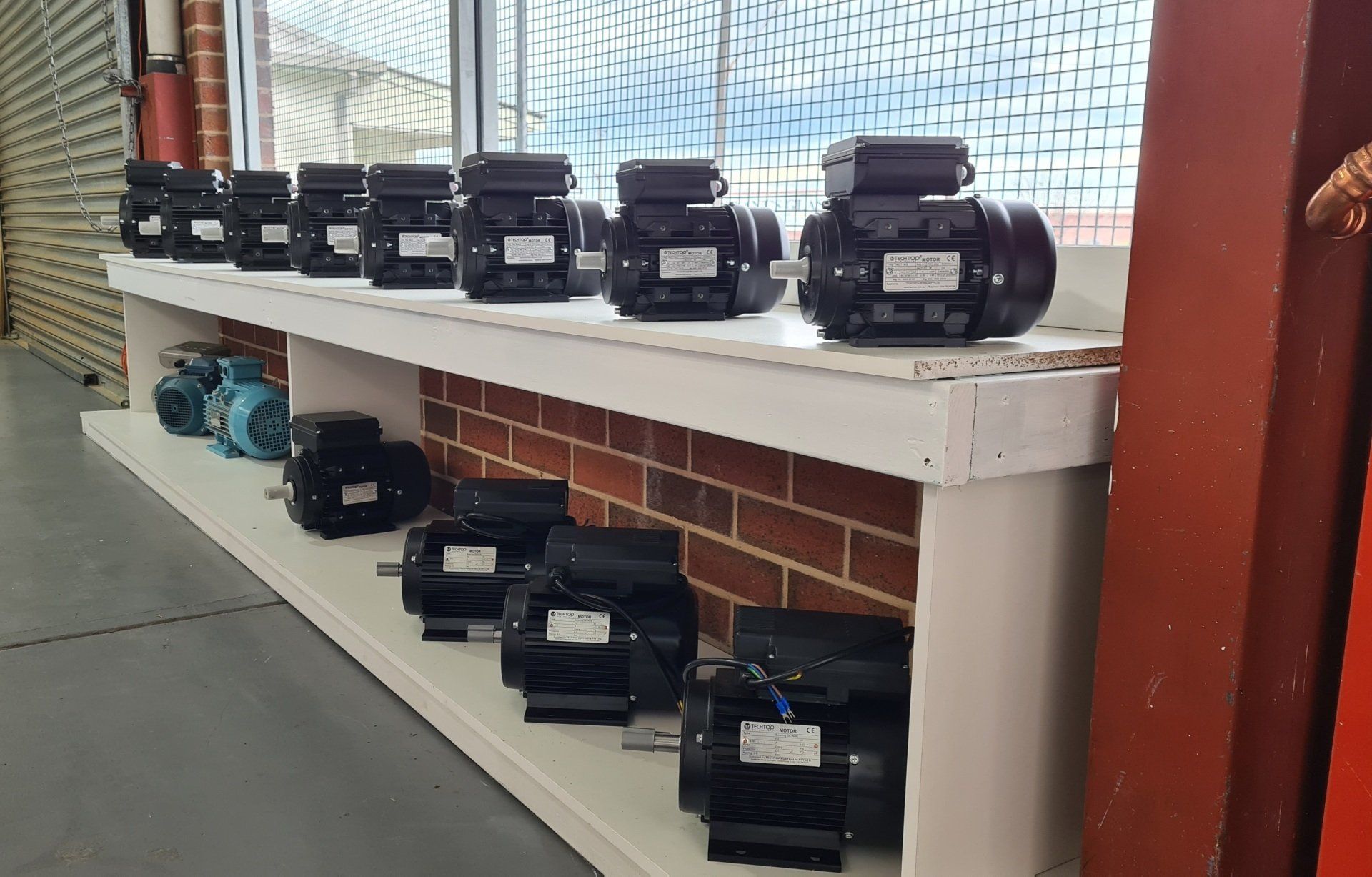 A row of black electric motors sitting on top of a shelf.