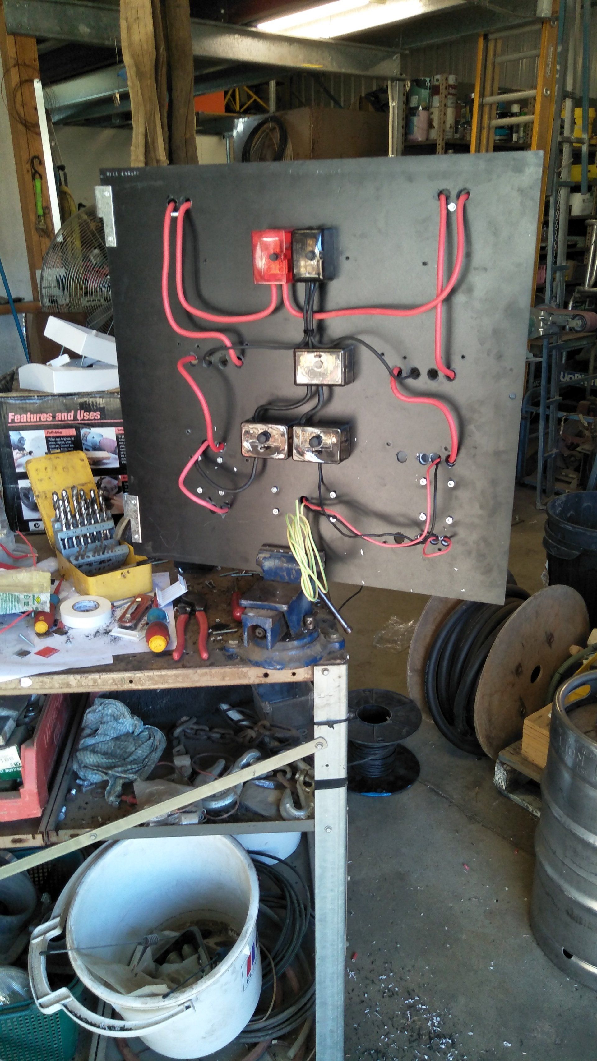 A board with electrical wires and tools on a table.
