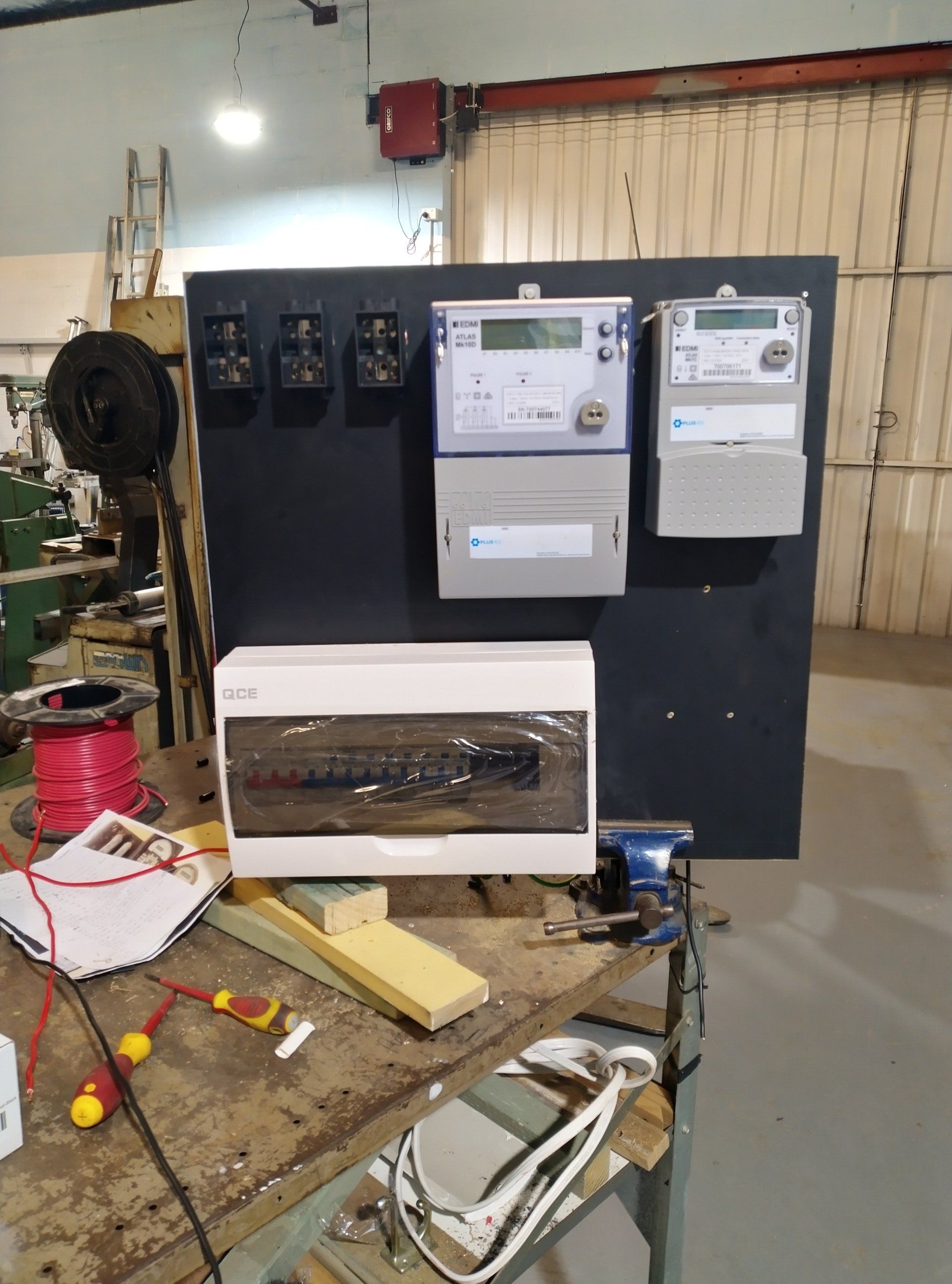 A board with electrical wires and tools on a table.