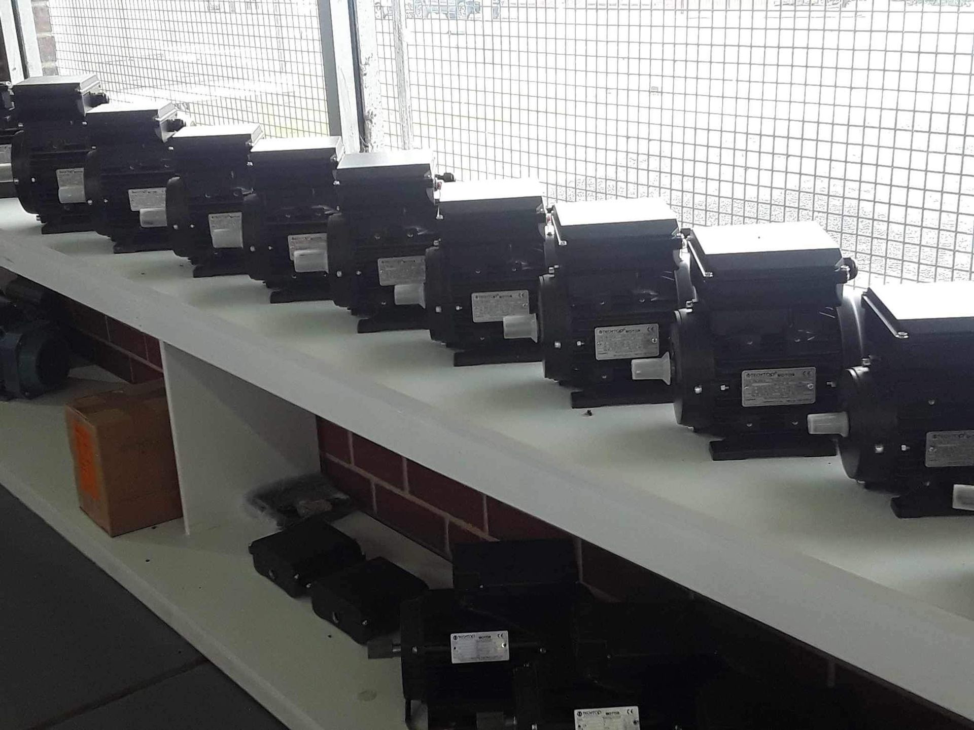 row of black motors sitting on top of a white shelf