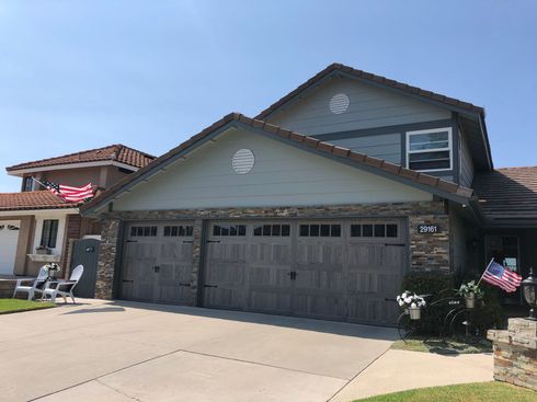 A large house with a large garage door and two american flags in front of it.