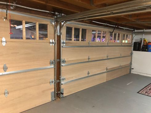 A wooden garage door is open in a garage.