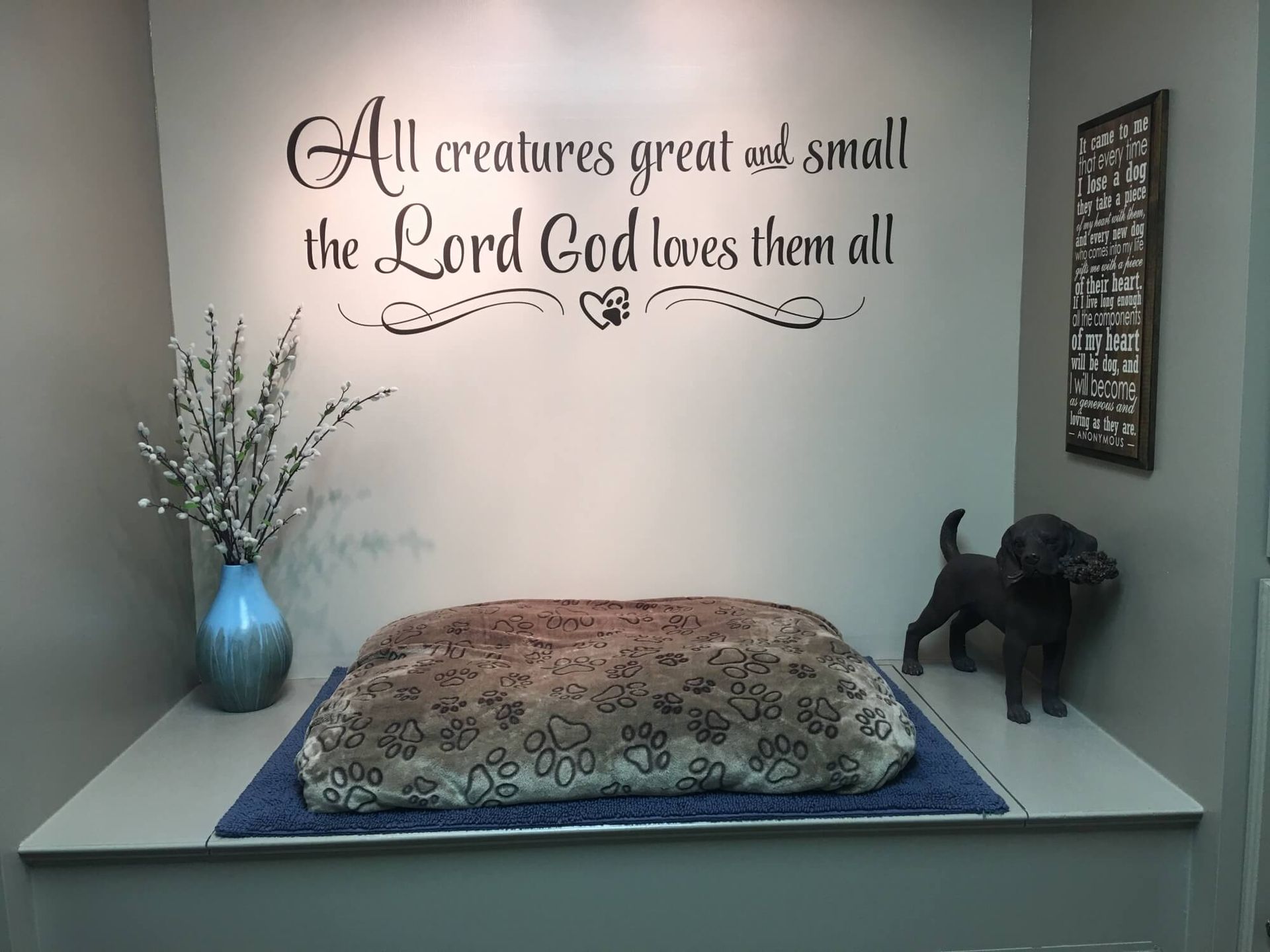 a dog bed under a wall that says all creatures great and small the lord god loves them all