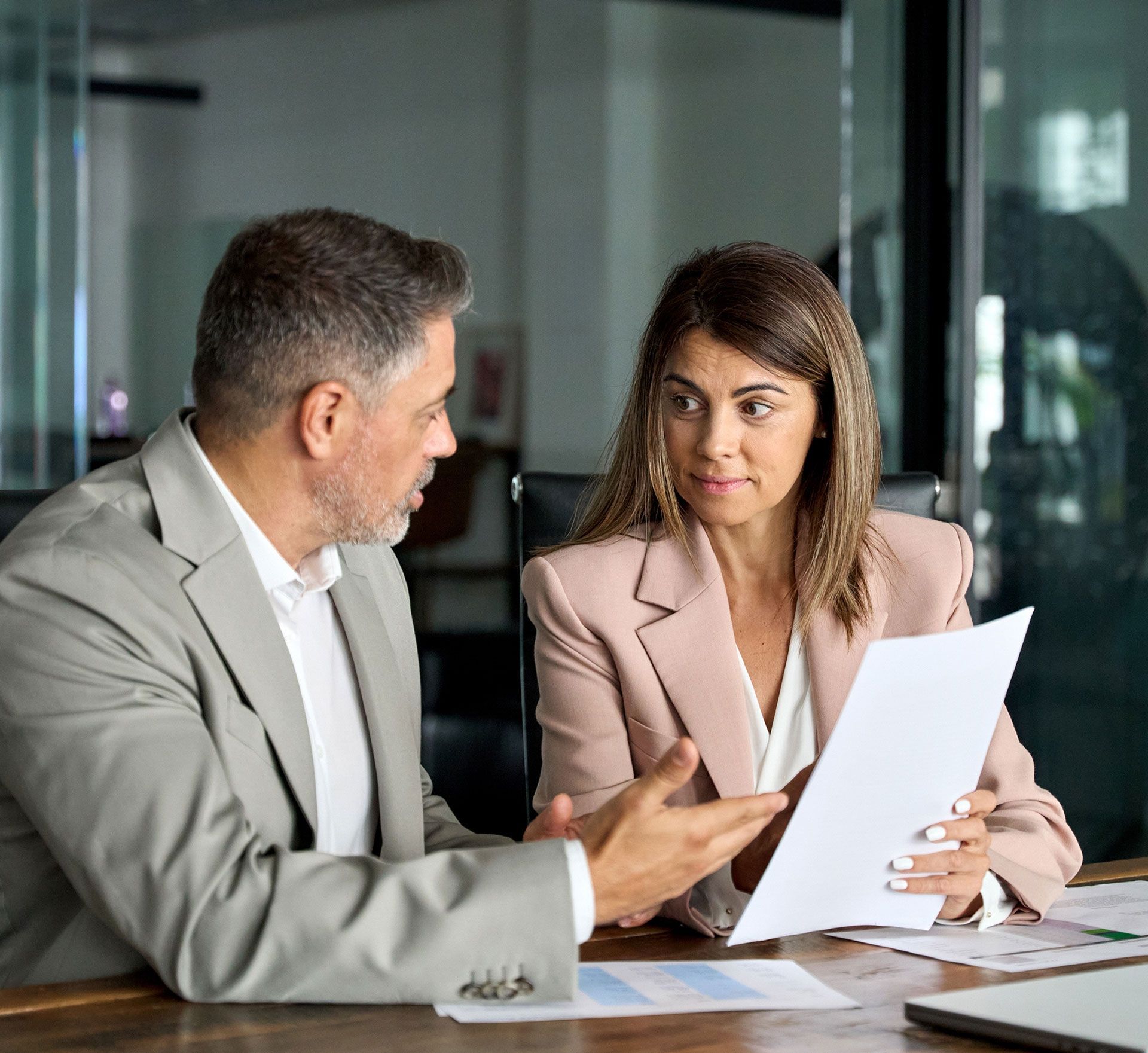 A man and woman reviewing documents in an office setting. They appear engaged in a discussion.