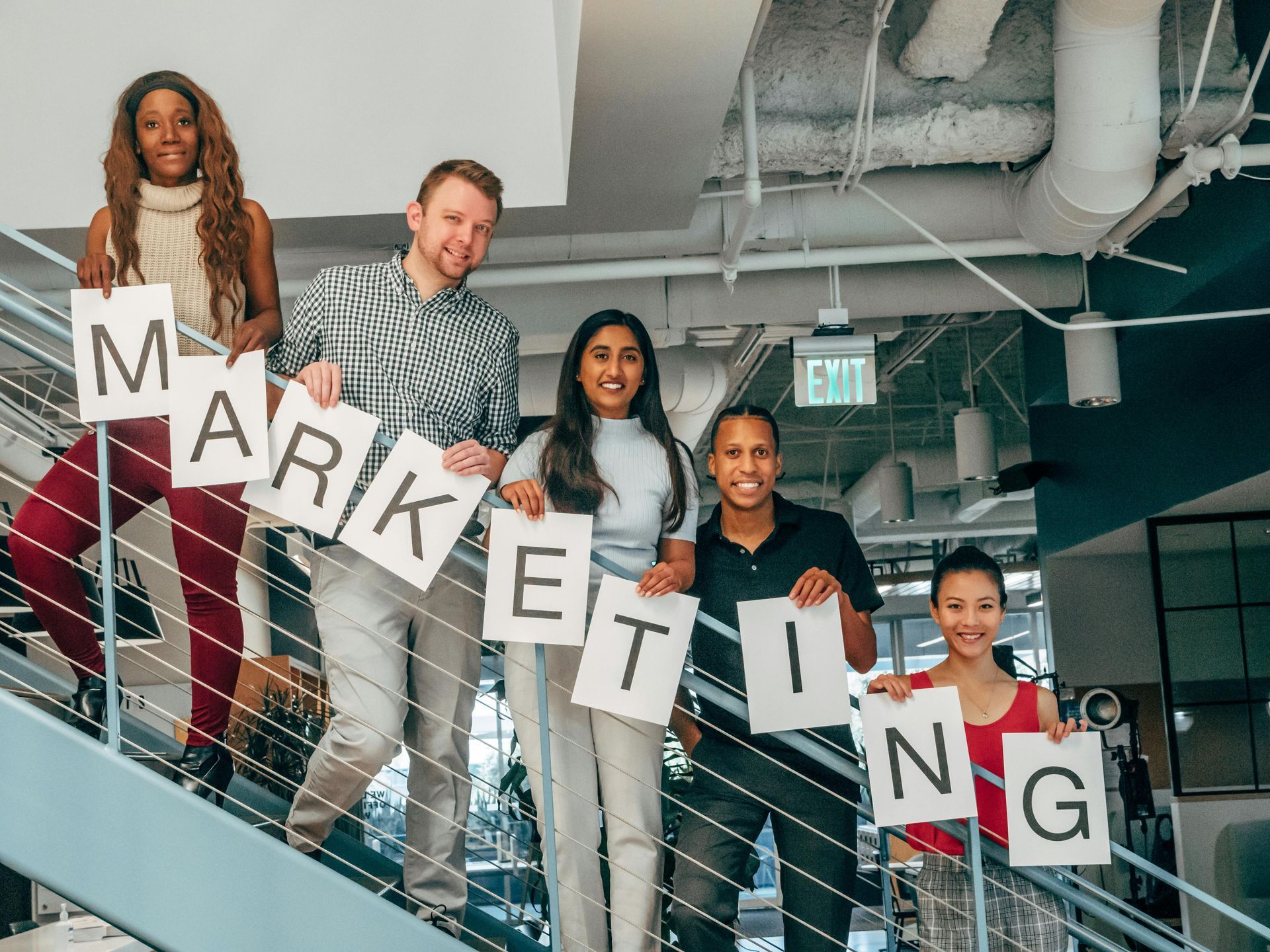 A group of people are standing on a set of stairs holding signs that say marketing.