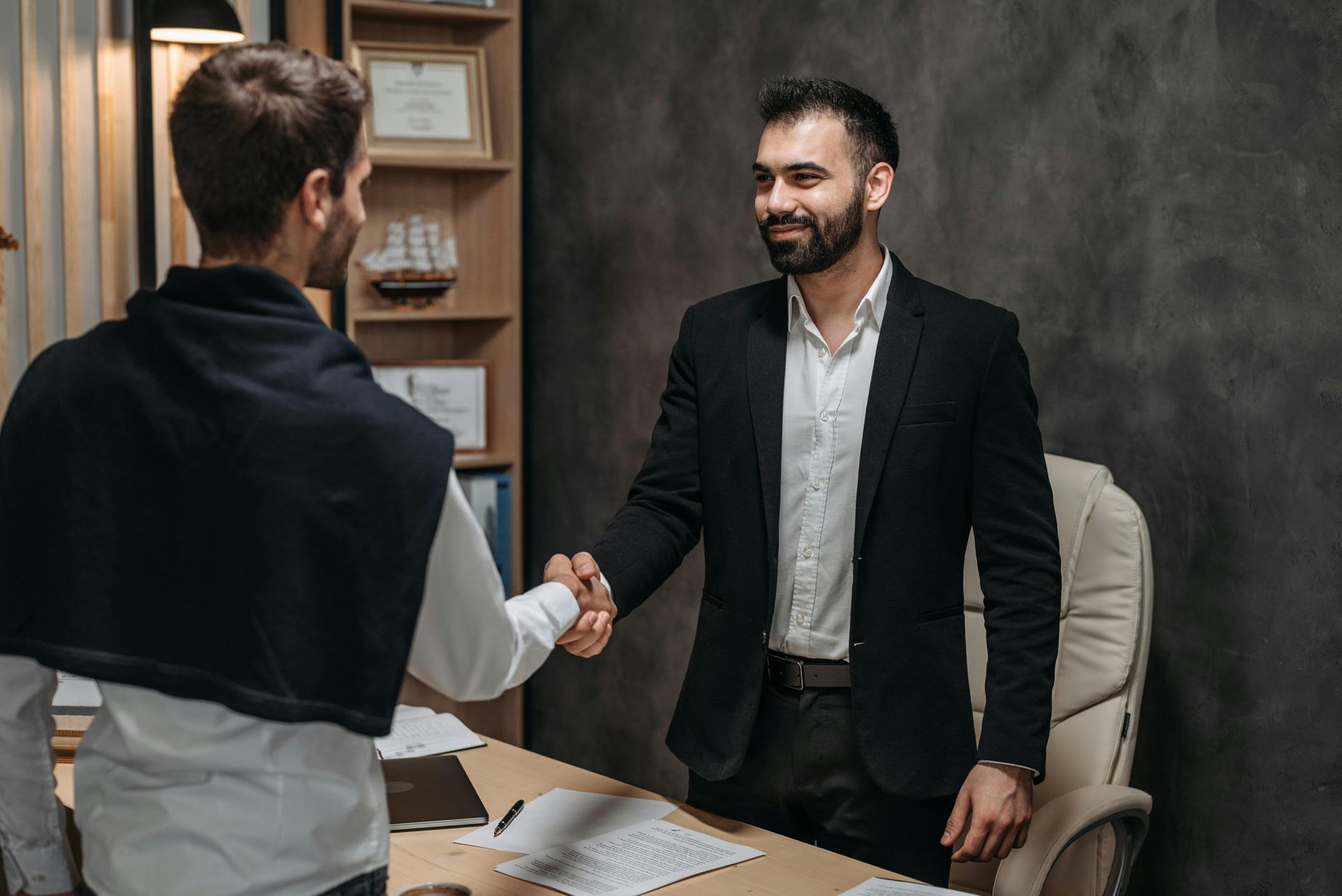 Two men are shaking hands in an office.