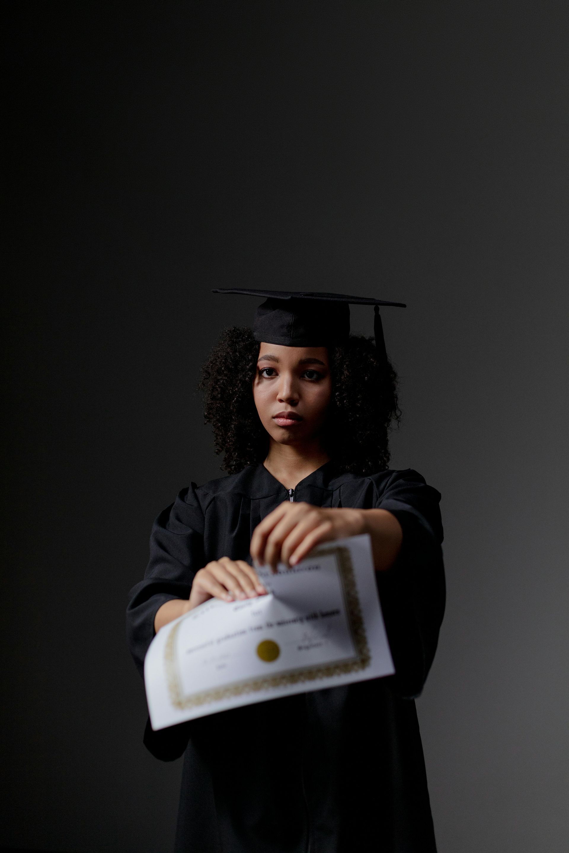 A woman in a graduation cap and gown is holding a certificate.
