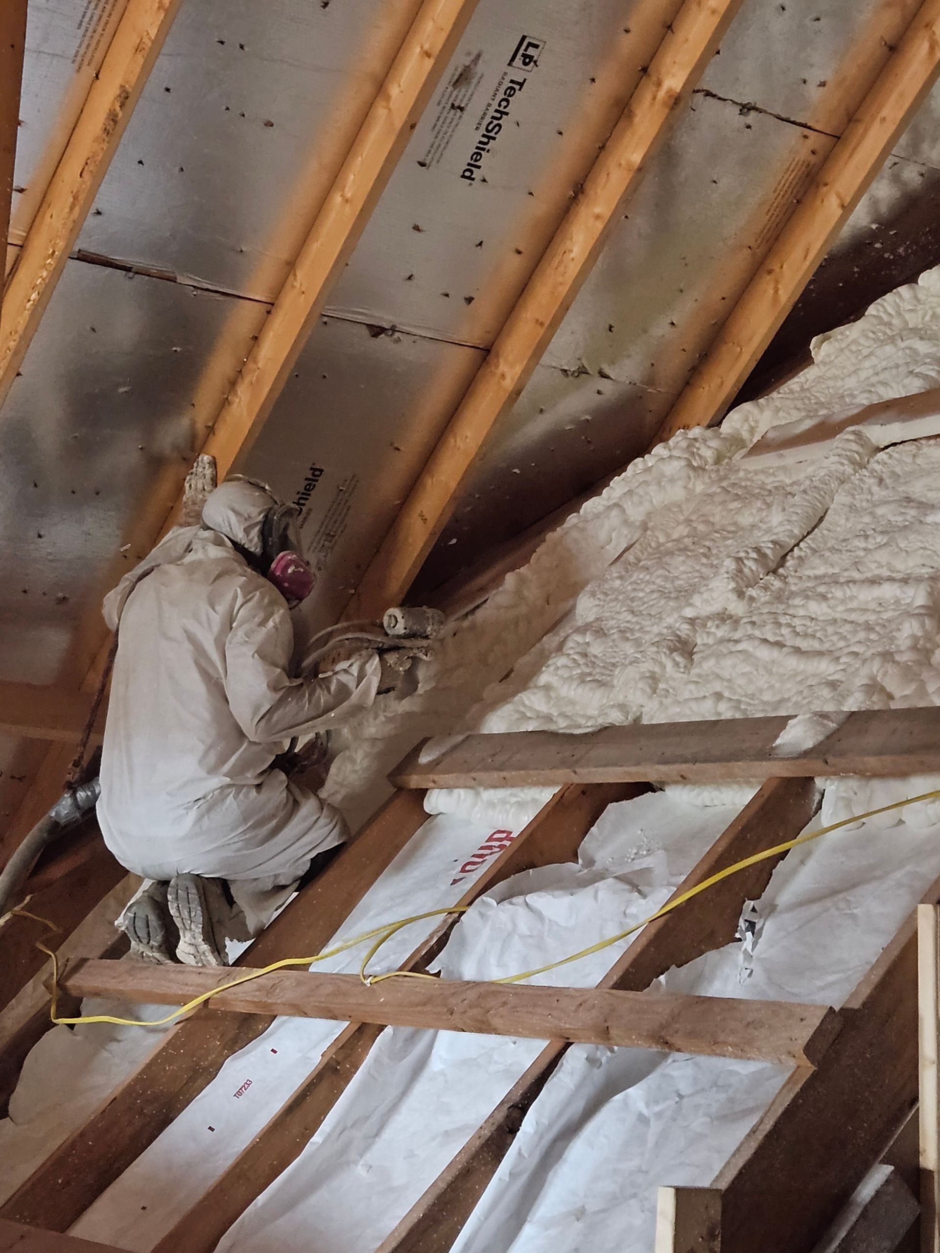A man is spraying insulation on the roof of a building
