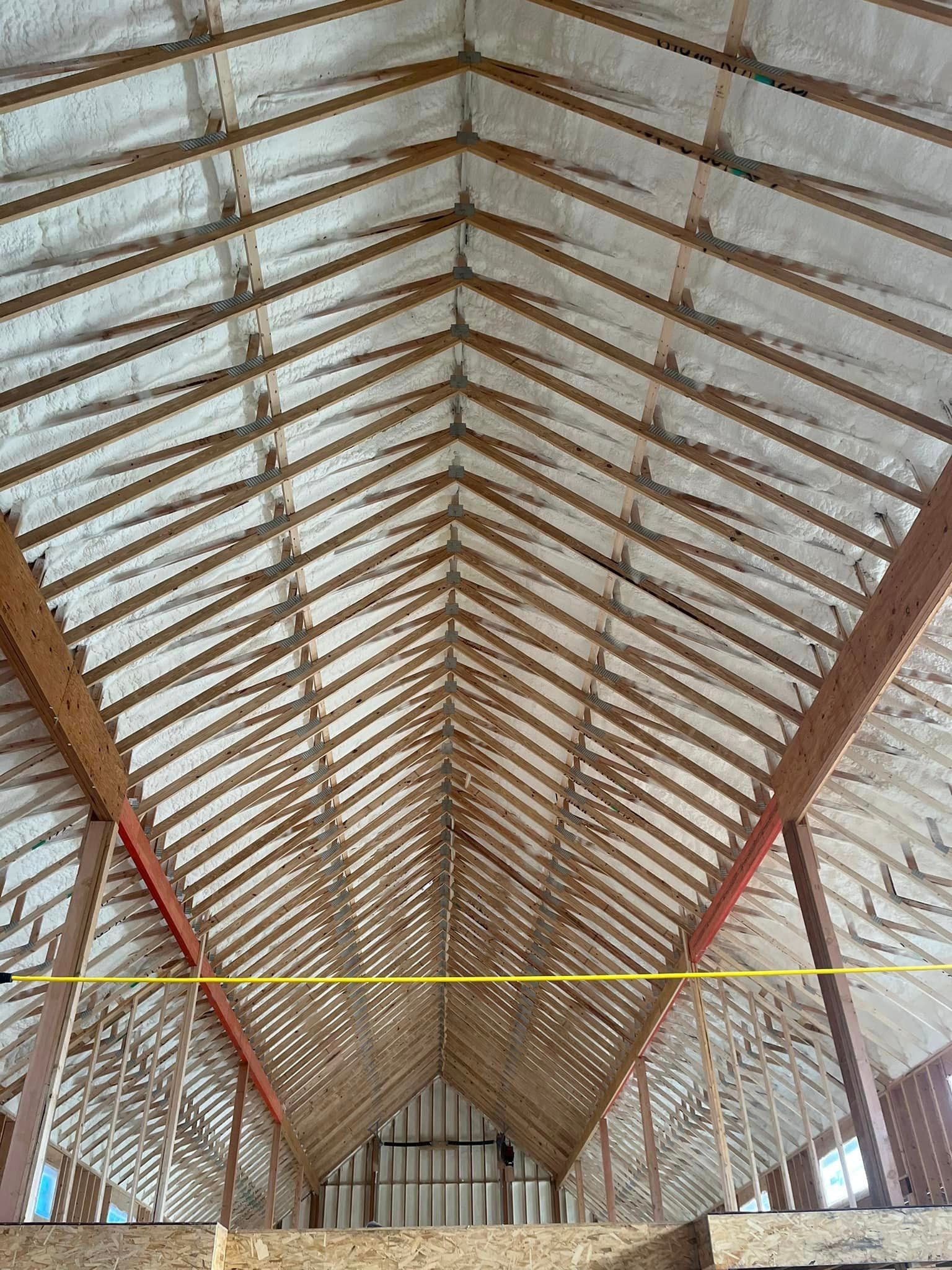 The ceiling of a barn is covered in foam and wooden beams.